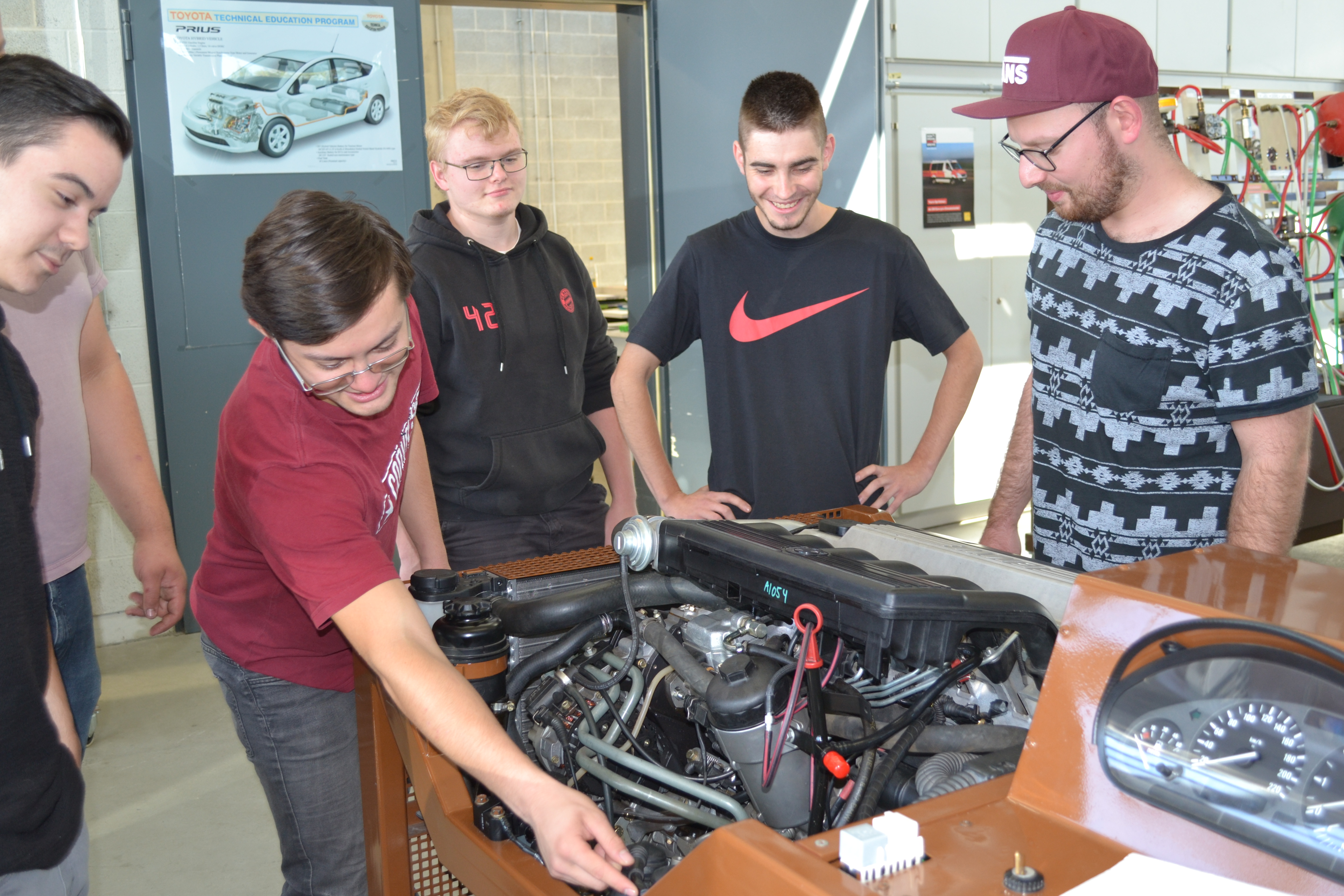 Auszubildende untersuchen ein funktionstüchtiges Motorenmodel